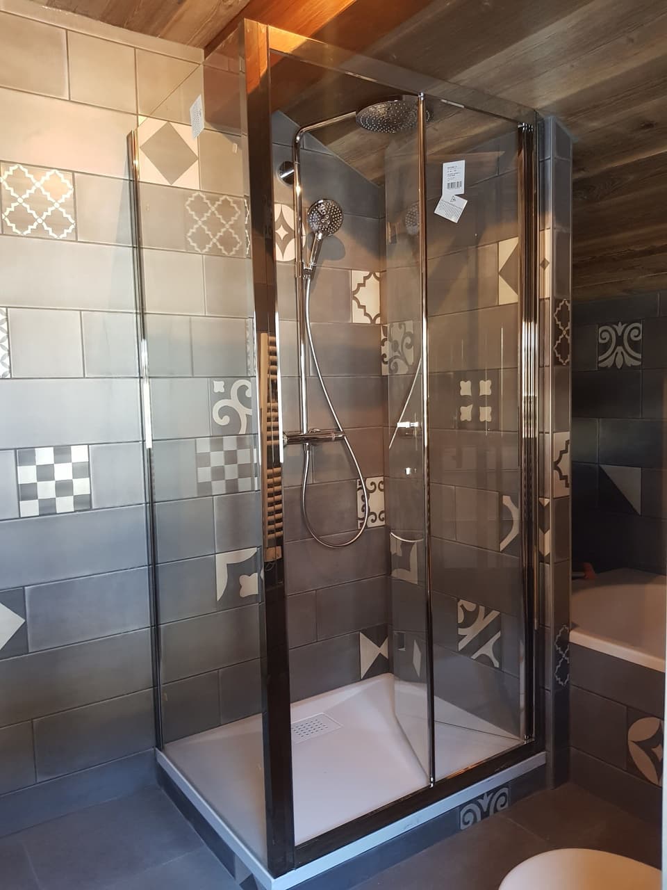 Cabine de douche vitrée avec colonne de douche et faïence façon carreaux de ciment, installée par KAT Plomberie