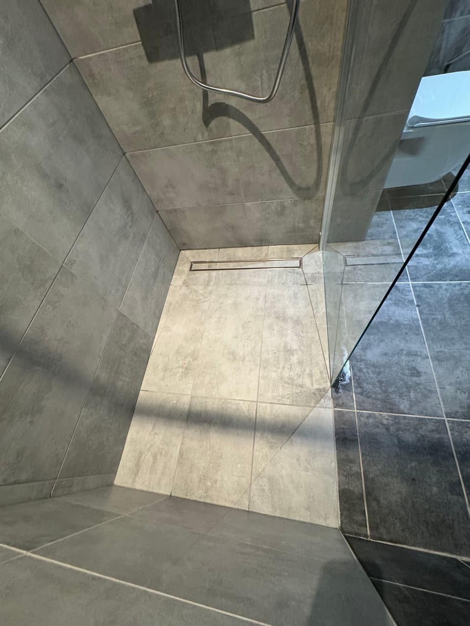 Douche à l'italienne avec receveur carrelé, caniveau inox et paroi vitrée posée par KAT Plomberie dans le Chablais